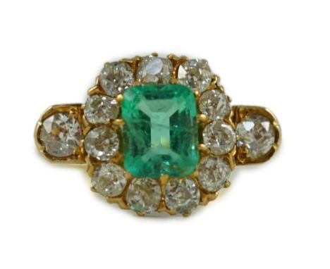 An 18ct gold, emerald and diamond octagonal cluster ring, with single emerald cut central stone and thirteen old cut diamonds