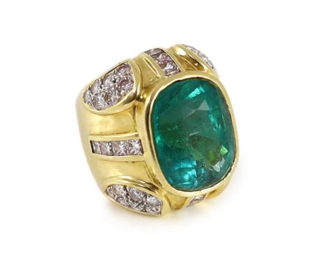 A large gold and single stone oval cut emerald set dress ring, with round and princess cut diamond cluster set shoulders, the