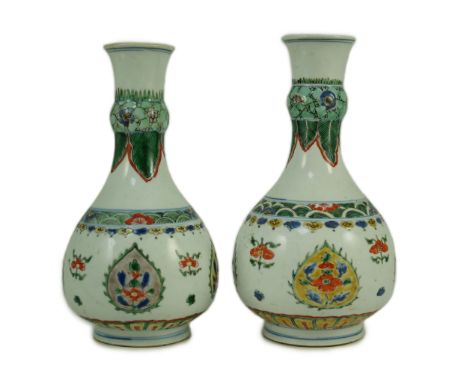 A near pair of Chinese famille verte garlic-neck vases, Kangxi period, each painted with flowers within teardrop shaped reser