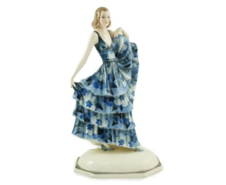 A Goldscheider Art Deco pottery figure of a dancer, modelled by Dakon, wearing a blue floral dress, on a canted rectangular d