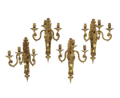 A set of four early 20th century Louis XVI style ormolu three branch wall lights with acanthus, flower and mask plates and sc