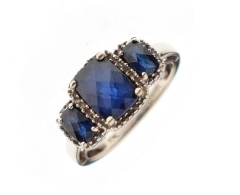 White metal dress ring set three graduated faceted sapphire coloured stones, the shank stamped 10K, size N, 3.4g gross approx