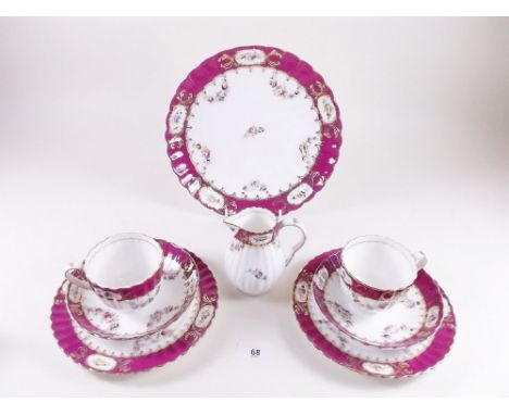 A Victorian tea service with painted floral swags and sprays within puce borders comprising: six tea cups and sixteen saucers