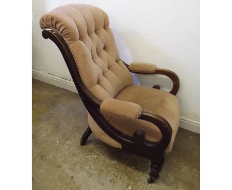 A Victorian mahogany button upholstered library chair with scroll over arms and turned supports with castors