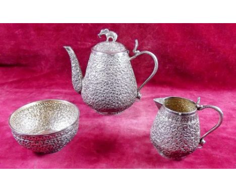 An Indian early 20th century white metal three piece tea service with all over floral decoration and elephant finial to teapo