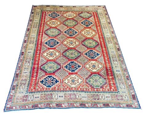 FINE KAZAK CARPET, 290cmx 214cm, geometric hooked medallions on an abrashed ruby field within corresponding bands and borders