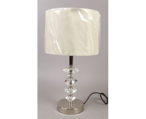 A modern table lamp with cut glass, chrome base and cream shade.