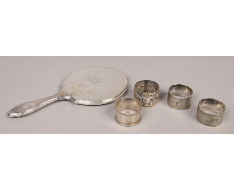 A silver mounted hand mirror, assayed Chester 1917, along with four silver serviette rings, one with repousse decoration hunt