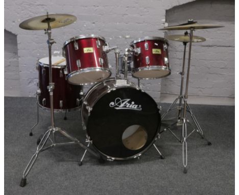 An Aria five piece drum kit with hi hat crash cymbals and stands along with a tripod stool and drumsticks.