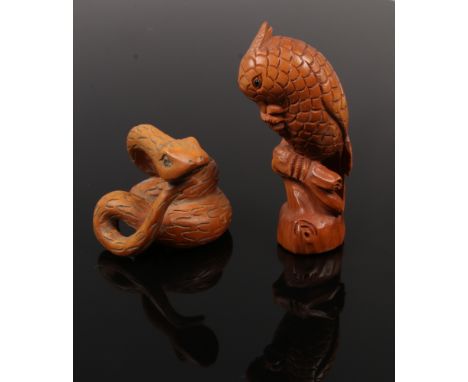 A carved fruit wood netsuke of a perched parrot with glass set eyes, signed, along with a similar carving of a coiled snake.
