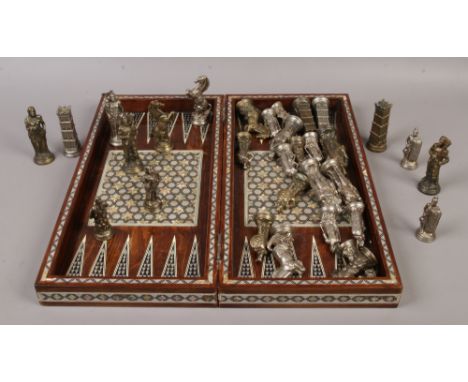 A hardwood folding chessboard / backgammon with mother of pearl inlay, along with metal figural chess pieces.