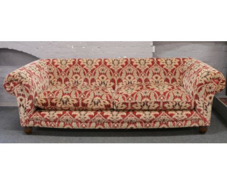 A very large good quality three seat sofa in red and gold velvet moquette upholstery rasied on reeded bun feet, four contrast