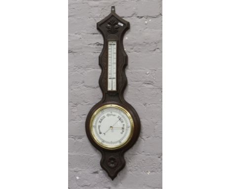 An early 20th century carved dark oak banjo barometer with porcelain dial.