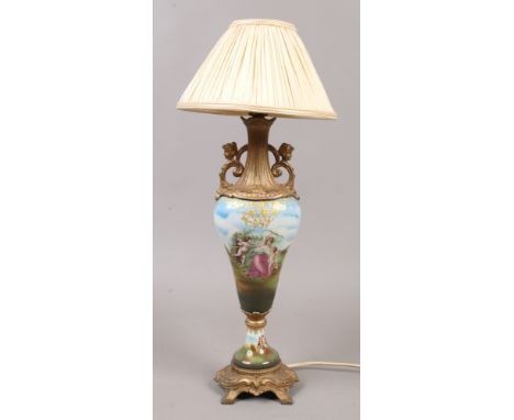 A continental porcelain and gilt metal table lamp decorated with putti and cream silk shade.