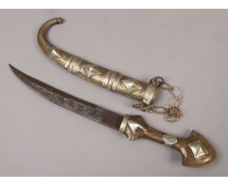 A Middle Eastern Persian style dagger in brass and white metal scabbard.