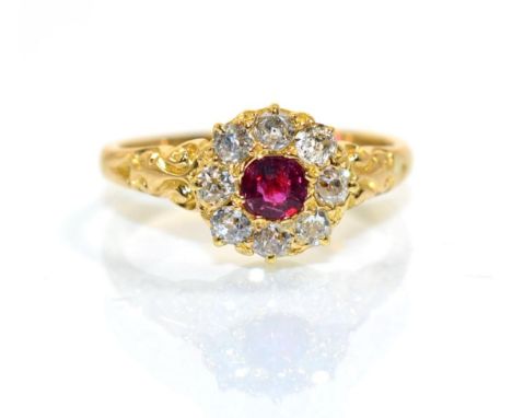 A ruby and diamond cluster ring, a round cut ruby within a border of old to diamonds, to scroll shoulders, total estimated di