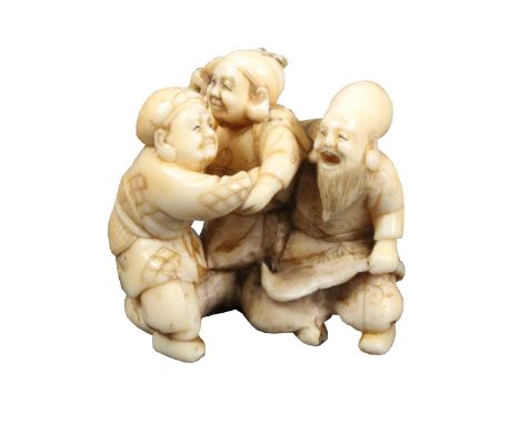 A 19th Century Japanese carved ivory netsuke of three male figures, two wrestling, the other a bald bearded man with fan, 4.5