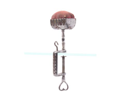 A steel sewing clamp the rectangular frame with elegant hook and heart pierced screw terminal below a trough form pin cushion