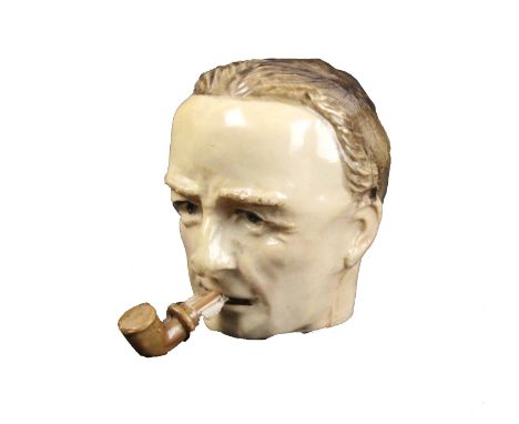 A celluloid novelty tape measure in the form of the head of man, the tape printed in cm and inches and emerging from his pipe