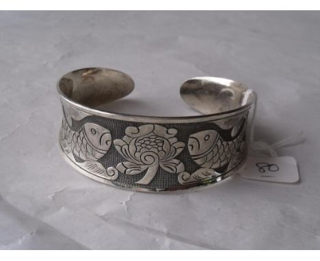 An Oriental silver torque bangle chased with fish   and lilies 30g        