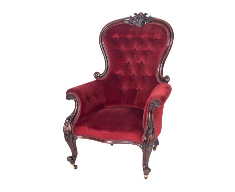 A Victorian carved mahogany armchair, with upholstery to match the previous lots, the cartouche-shaped button down panel back
