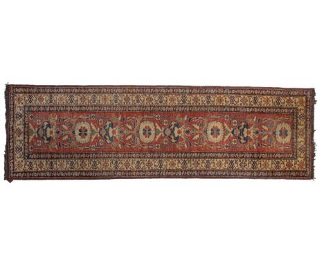 A Turkish Sirvan runner, the brick red field with a design of stylised flowers and foliage and flowerhead medallions, enclose