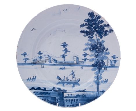A Bristol blue and white delftware dish painted with a large country mansion with sponged trees around a lake, a boat with th