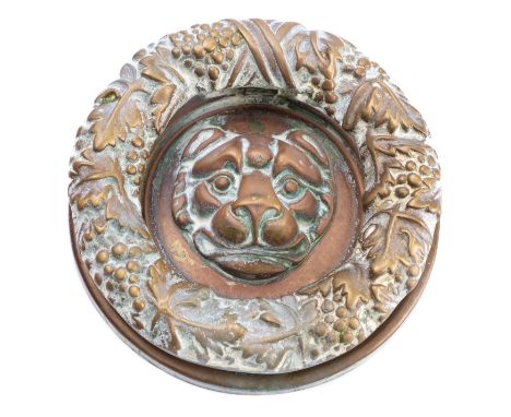 A heavy brass door knocker in Regency style, circa 1900; the hinged knocking ring cast with tied fruiting grapevines, on a ci