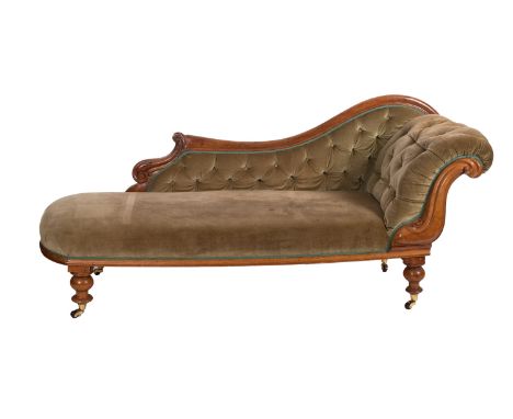 A Victorian carved walnut chaise longue, with an upholstered button down three quarter shaped back and scroll end with foliat