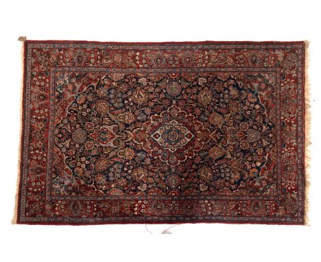 A Kashan rug, the indigo cartouche field with a central red, ivory and pastel blue lozenge pole medallion, all over floral fo