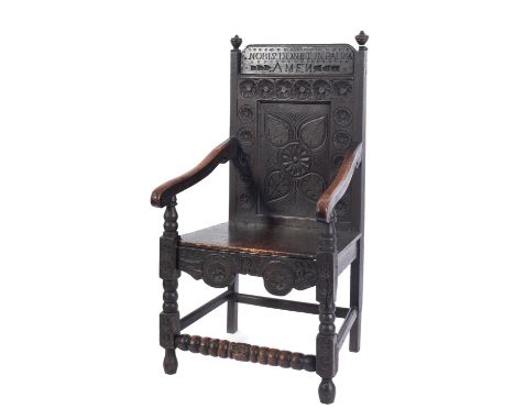 A carved oak wainscot elbow chair in late 17th century style, 19th century; the rectangular backrest inscribed NOBIS DONET IN
