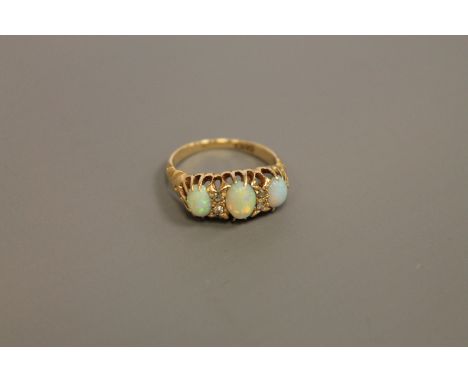 A three stone opal and diamond set ring CONDITION REPORT: Good condition. Ring size K. Set with four old cut diamonds. 4.0g. 