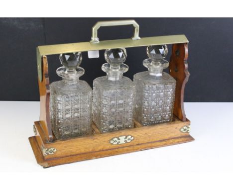 Early 20th Century oak tantalus housing three cut glass decanters with faceted stoppers. Marked C7026. Measures 35cm wide. 