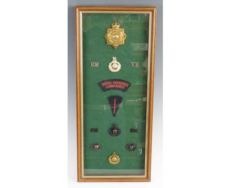 A framed display of Royal Marines insignia to include helmet plate, R.M. Commandos cloth shoulder title and cap badges, 56 x 