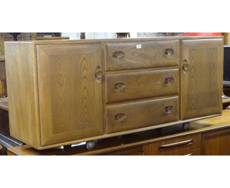 An Ercol elm sideboard, with 3 frieze drawers and panelled cupboards, W155cm, H69cm 