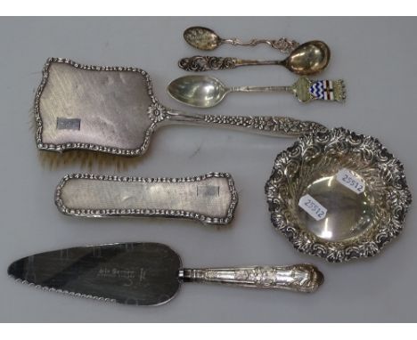 A box of silver items, to include 2 silver-backed brushes, a silver and enamel spoon for L.C. Lodge, a Norwegian silver spoon