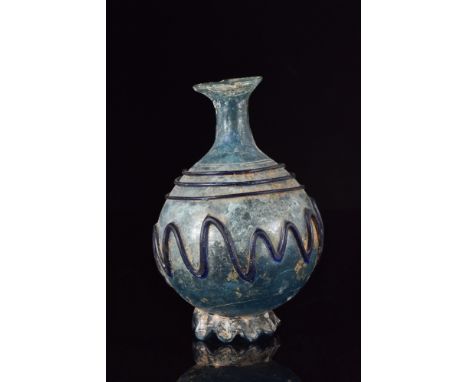 Ca. 300 AD.A stunning pale blue glass bottle featuring a finely modelled piriform body decorated with elegant trailing, set u