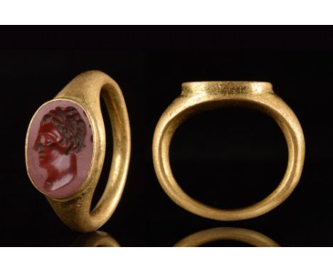 Ca. 100-300 AD.A gold finger ring with a D-shaped tapering shank; an oval bezel set with a red stone intaglio engraved with a