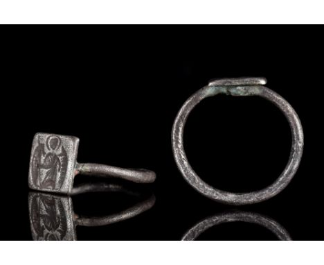 Ca. 1000 AD.A silver finger ring featuring a square-shaped bezel connected to a thin round-section hoop. The bezel is decorat