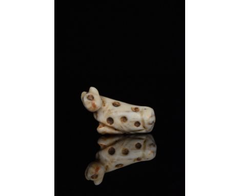Ca. 2500-2200 BC.A lovely fossilised shell amulet carved in the shape of a recumbent lion. The animal presents an erect head,
