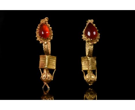 Ca. 100-300 AD.A pair of elaborate gold earrings composed of a large tear shaped garnet which encircled by granules, below th