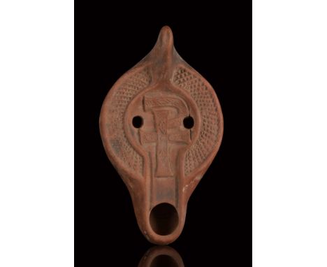 Ca. 600 AD.A beautiful terracotta oil lamp featuring a recessed discus with two parallel filling holes and adorned with a Chi