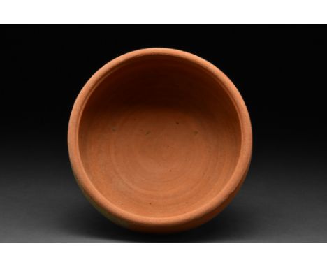 Ca. 300-400 AD.A terra sigillata dish comprising a round-bottomed bowl with high sides that end in a thick everted rim. Terra