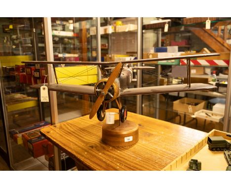 A large wooden model of a WW1 style RFC/RAF bi-plane. A simplistic model painted in dark brown with propeller, gun, pilot, un