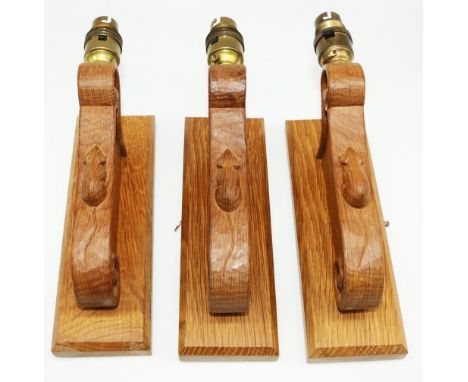 Robert Mouseman Thompson of Kilburn - a set of three oak wall lights, scrolled support on square bracket, carved with signatu