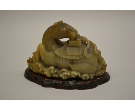 19th Century Chinese carved brown and green variegated jade figure of a reclining horse with saddle above stylised waves on a