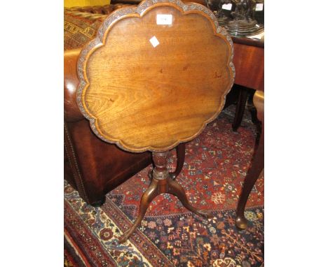 Small late 19th or early 20th Century mahogany pedestal table, the shaped tilt top with carved and shaped moulded rim raised 