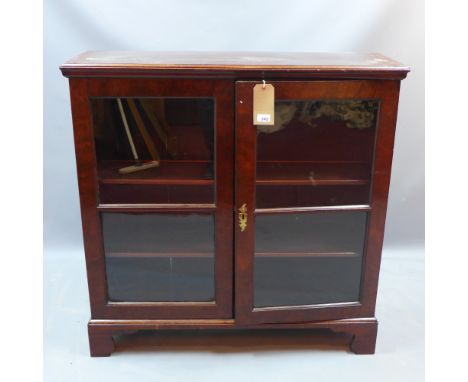 A 19th century mahogany display cabinet with two glazed doors enclosing adjustable shelves and raised on carved bracket feet,