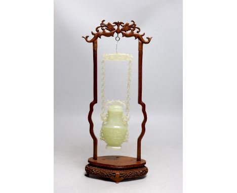 A Chinese bowenite jade hanging vase and cover together with a carved hard wood stand, one foot missing, 42cm tall