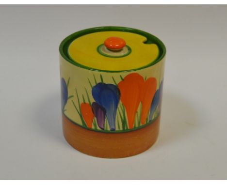 A Clarice Cliff Crocus pattern cylindrical preserve pot and cover, painted in colours with crocuses, banded in yellow and tan